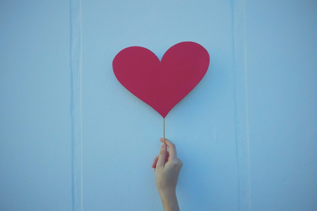 A person holding a red heart-shaped balloon