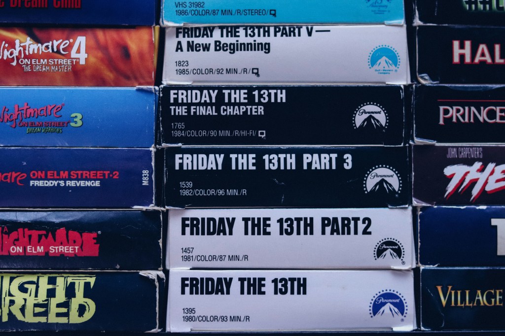 A pile of old VHS tapes of Friday the 13th and Friday the 13th part 2
